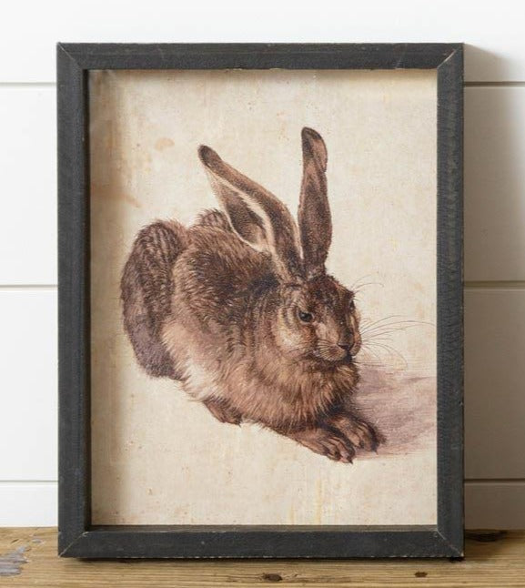What a sweet little picture of a rabbit sitting.  We love the neutral black and tan colors of this print that make it so easy to put in any decor! The black distressed shadow box frame makes this irresistible not to take home!  11