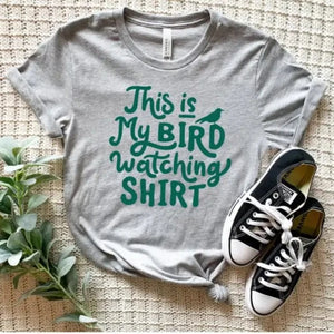 <span data-mce-fragment="1">This fun heathered grey tee has the words words "This is my birdwatching shirt" in a teal green font with a bird perched on the "d" or the word "bird."&nbsp; It's a great t-shirt to spread some positive vibes! </span><span data-mce-fragment="1">Printed direct-to-fabric printing for a soft design that won't crack or peel. The shirts are soft Bella and Canvas unisex fashion-fit tees that fit like a well-loved favorite, featuring a crew neck and short sleeves.</span>