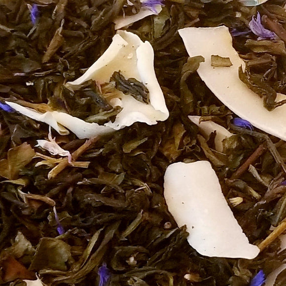 Coconut Grove Puchong Tea: A loose-leaf pouchong tea with blue cornflower petals in it and shaved slices of coconut all on a blue and white patterned plate.