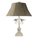 Two birds perch, ready to fly, under a shade, topped with a bird finial. This 24" table lamp is perfect for bird lovers or anywhere you want a touch of the outdoors brought inside. It comes with a beautiful shade lined in a brown and ivory bird toile fabric. Dimensions 12" l x 18" w x 24" h  Weight 7 lb  Available for pick-up only at this time