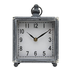 You'll love how this square clock will fit perfectly into your living room, bedroom, or even bathroom!  The charcoal grey metal washed finish has white distressing on the corners making it a great neutral piece in your home. It has a glass face and small metal ball feet and a ring accent on the top.  Ticking mechanism requires an AA battery not included.   6 x 3 x 7.5"H; Height with Ring: 8.5"; Clock face diameter: 5.9"  Metal & Glass