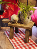 This distressed wooden stool is perfect for setting a plant, small lamp, or cute vignette on!  If you need to give something some height to your decor, this little stool will help you do just that!  Rectangle top.  4.5" H x 9.5" L, 4.75"D