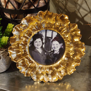 We love this gold leaf floral frame, and we know you'll love putting your favorite photo in it! The petals are folded out for extra dimension surrounding the circular photo area. it will stand for a tabletop display or can hang.  Dust with a dry, soft cloth. Resin Frame: 3/4" D x 7 1/4" Dia Picture Opening: 4" x 4"