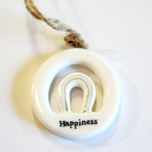 This little circular porcelain gift tag is sure to bring a little happiness to you or someone you give it to!  Inside the cut-out is a rainbow, and below it is the word "Happiness. A jute rope is attached at the top for hanging.  1 1/4" Dia