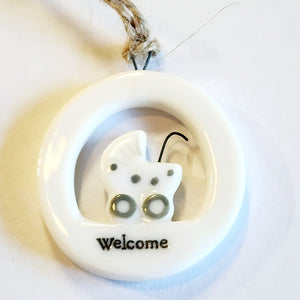 This little circular porcelain gift tag is sure to bring a little happiness to you or someone you give it to!  Inside the cut-out is a baby carriage, and below it is the word "Welcome." This makes a great gift for a new parent and a sweet sentiment for the new baby of the family! A jute rope is attached at the top for hanging.  1 1/4" Dia