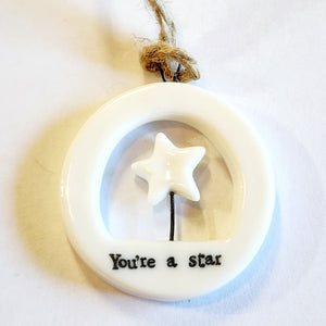 This little circular porcelain gift tag is sure to bring a little happiness to you or someone you give it to!  Inside the cut-out is a star on top of a black stick; below it is the word "You're A Star." A jute rope is attached at the top for hanging.  1 1/4" Dia