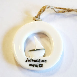 This little circular porcelain gift tag is sure to bring a little happiness to you or someone you give it to!  Inside the cut-out is a sailboat; below it is the word "Adventure Awaits." A jute rope is attached at the top for hanging.  1 1/4" Dia