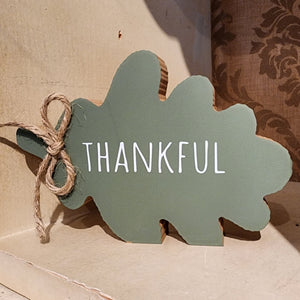 This green wooden leaf is shaped like an oak leaf and says "thankful" on it.  Finished with a little jute bow, it will look beautiful mixed in with your other fall decor this year!  4.5”H x  5.75W x 1”D 
