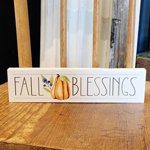 This mini white sign has the words "Fall Blessings: in a block font with an orange pumpkin and blue colored berries off to the left, between the words "Fall" and "Blessings."    Wood Depth: 0.4375" Width: 6" Height: 1.5"