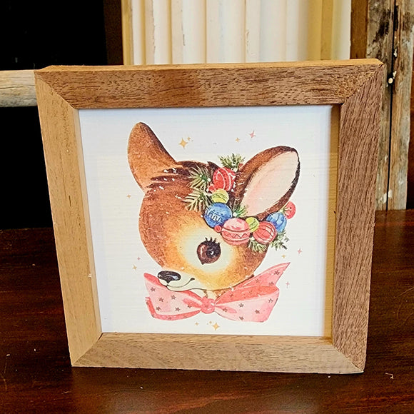 This adorable vintage doe has a pink bow and a vintage Christmas bulb wreath around its ear. It will surely be your favorite little picture to decorate with this holiday season!  It is made from high-quality American hardwood planks with a hand-painted face, printed with UV-cured ink, and framed in a natural walnut frame. Each piece is unique with its own personality, marks, wood grain, and look. Easy to clean with a dry cloth.  Made in the USA  4