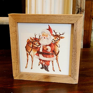You'll love the look of this retro Santa with two of his reindeer. You'll love decorating with this miniature artwork even more this holiday season!  It is made from high-quality American hardwood planks with a hand-painted face, printed with UV-cured ink, and framed in a natural walnut frame. Each piece is unique with its own personality, marks, wood grain, and look. Easy to clean with a dry cloth.  Made in the USA  4" x 4" x 1"