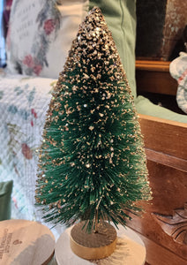This beautiful emerald-green tree has gold glitter cascading from its top and is perfect for accenting any space in your home.   Materials: Glittered bottle brush.  Dimensions: 10" X 5" X 5"