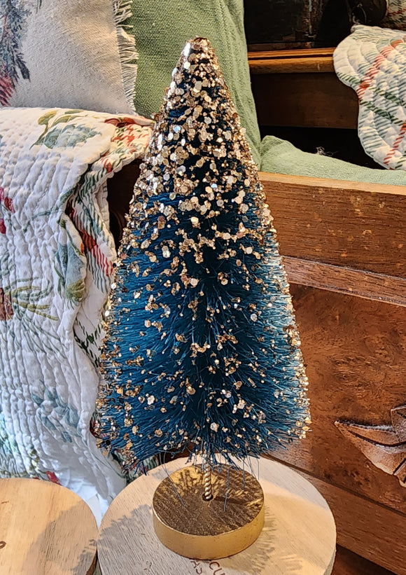This beautiful turquoise tree has gold glitter cascading from its top and is perfect for accenting any space in your home.   Materials: Glittered bottle brush.  Dimensions: 8