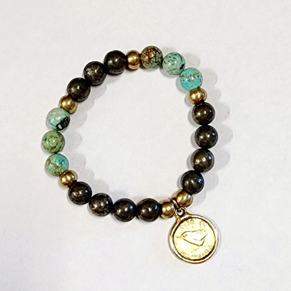 Wear one or stack them high. Our Gemstone Stretch Beaded Bracelets go with anything. Beautiful blue turquoise and pyrite beads are threaded on a stretch band with six gold beads and a gold coin on it.  On one side of the coin is a bird with the date 1938 above and the word 