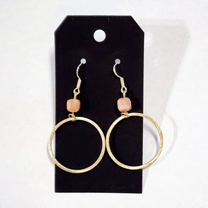 These stylish earrings have a peach bead hanging above the brushed gold circle  Approximately 2.75" in length. 