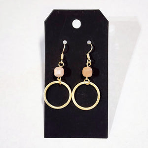 These stylish earrings have a peach bead hanging above the brushed gold circle  Approximately 2.25" in length.