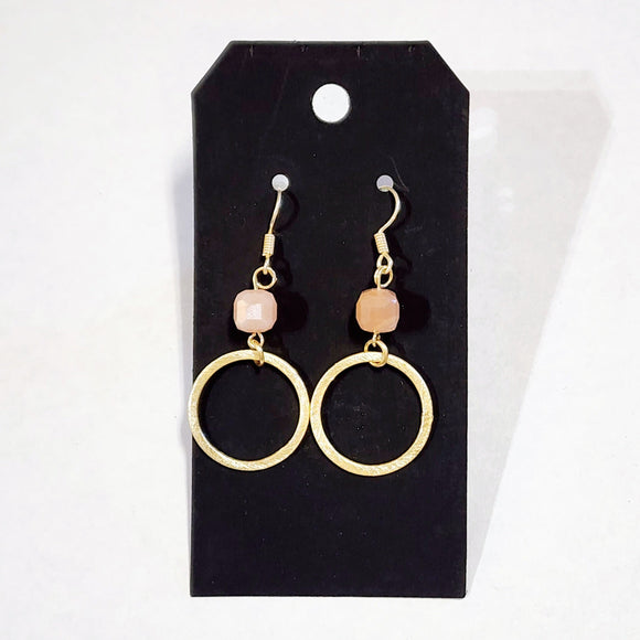 These stylish earrings have a peach bead hanging above the brushed gold circle  Approximately 2.25