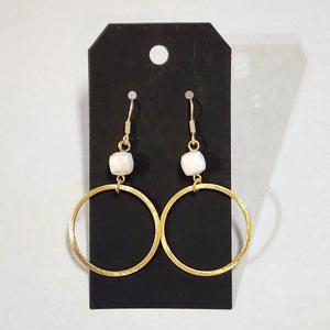 These stylish earrings have a white bead hanging above the brushed gold circle  Approximately 2.75" in length. 