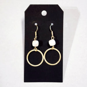 These stylish earrings have a white bead hanging above the brushed gold circle  Approximately 2.25" in length. 