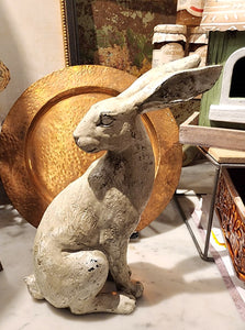We are loving our new distressed rabbit! She will look great mixed in with your decor. Pair her with our other distressed rabbit, a little smaller with his ears up. This distressed rabbit is sitting up, looking behind his left shoulder and her ears are straight back. Her finish has a distressed grey wash over a cream base color.  10.25" H x 7.5" W x 3.5" D  Polyresin, Stone Powder