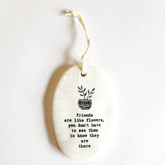 This oval-shaped porcelain ornament has a potted plant up top and says 