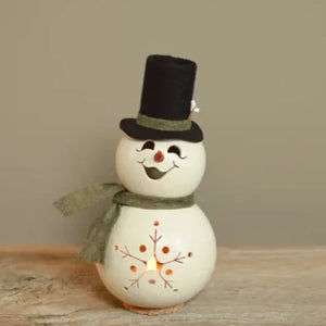 This little snowman will warm your heart! His smiling face is hand-cut, as well as the snowflake on his belly. He comes with a sweet “carrot” clay nose. This black felt top hat is adorned with white winter berries and green detailing that matches his green scarf. This snowman sits on a removable cork base that allows you to light the design with a battery-operated tea light (sold separately).