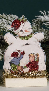 This vintage-inspired wooden snowman has two children packing snow on his belly. This board looks cute mixed in with your other Christmas decor or standing alone!
