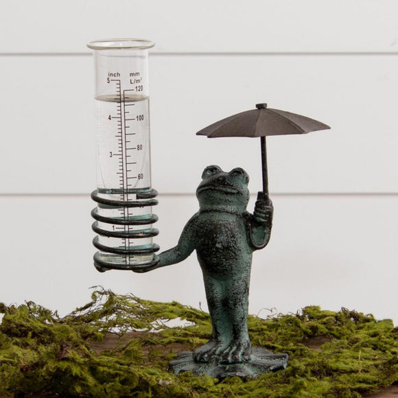 This adorable frog rain gauge will make you smile when you see the rain! He's standing on his lily pad (as well as himself), which is brown in color but covered in a green patina rub. He is holding a brown umbrella. He holds the glass rain gauge in his right hand. The rain gauge is removable.  9 H x 6.5 W x 3.5 D Iron & glass