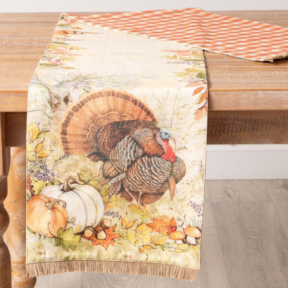 Get ready for fall with our turkey and pumpkin table runner! The front has a beautiful watercolor-style turkey with pumpkins, leaves, and acorns. The reverse side is a pretty orange, cream, and brown plaid. The runner has an accent burlap fringe at the bottom of each side.    72