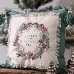 This gorgeous pine green pillow will be a beautiful addition to your holiday decor this year! On top of the green is a frayed cream square that has been stitched onto the pillow.  On it, is a pinecone wreath, and inside it says "Heaven and Nature Sing"   18" H x 18" W