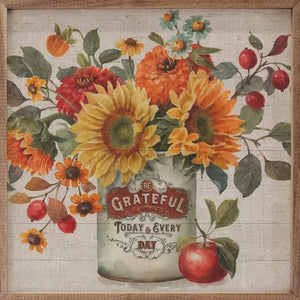 In brilliant oranges and reds, sunflowers and berries are in a container that says "Be Grateful Today & Every Day" on it by artist Lisa Audit.  An apple sits to the right of the container.  You'll love tucking this in your fall decor!