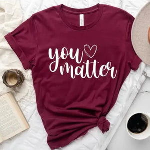 <span data-mce-fragment="1">This beautiful burgundy tee has the words "You Matter" in a cursive font with a heart after the word you. It's a great t-shirt with positive vibes! </span><span data-mce-fragment="1">Printed direct-to-fabric printing for a soft design that won't crack or peel. The shirts are soft Bella and Canvas unisex fashion-fit tees that fit like a well-loved favorite, featuring a crew neck and short sleeves.</span>