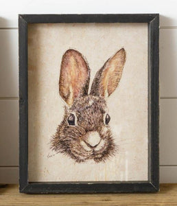 What a sweet little picture of an adorable rabbit's head!  We love this print's neutral black and tan colors, making it so easy to put in any decor. The black distressed shadow box frame makes this irresistible not to take home!  11" H x 8.75" W  Fir Wood, MDF, Glass, Paper