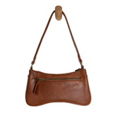 Meet Nicolette, our sleek, curvy cognac colored crossbody pochette with a minimalist style. Featuring soft sculptural curves in tumbled vegan leather, this bag is closed with a brass zipper that encloses 3 interior compartments to keep your cards, cash, keys and phone stowed neatly. The gleaming brass rings open to swap out the two included shoulder straps. A short strap for dressier looks and a longer adjustable crossbody strap when you want to go hands free. Available in an array of beautiful colors, the 