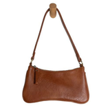 Meet Nicolette, our sleek, curvy cognac colored crossbody pochette with a minimalist style. Featuring soft sculptural curves in tumbled vegan leather, this bag is closed with a brass zipper that encloses 3 interior compartments to keep your cards, cash, keys and phone stowed neatly. The gleaming brass rings open to swap out the two included shoulder straps. A short strap for dressier looks and a longer adjustable crossbody strap when you want to go hands free. Available in an array of beautiful colors, the 