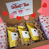 Tea box with yellow tea bags and a decorative card on a heart-themed background