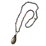 A beautiful long necklace with sections of glass beading with knots in between each bead with a gorgeous oval India Agate pendant that has a flower detail at the top of the stone. The back of pendant is bronze with scrolled details&nbsp;

Please expect some variation in color/texture due to natural material.

Length: 17" L ( 34" total) with a 2" L pendant