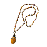A beautiful long necklace with sections of crazy agate glass beading with knots in between each bead with a gorgeous oval pendant that has a flower detail at the&nbsp;top of the stone. The back of pendant is bronze with scrolled details&nbsp;

Please expect some variation in color/texture due to natural material.

Length: 17" L ( 34" total) with a 2" L pendant