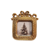 You'll love using this ornate gold photo frame with a fancy gold bow on the top! Leave the winter tree picture in, or change it to a fun family photo!

Approximately 5" W x 5.25" H&nbsp;