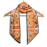 This orange scarf has flowers and butterflies in creams, reds, yellows and turquoises with a dark turquoise blue border.

Approximately 57" L x 5.25" W

100% Polyester
