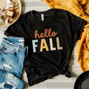 Hello, FALL! Celebrate the season with this very fun black T-shirt. It says "hello" in cursive orange font, and below it says "FALL" in an assorted colored font. This shirt is super comfy; you'll never want to take it off!&nbsp;  Before you purchase and decide on the right size for you, please make sure to compare measurements against our size chart. We recommend taking a t-shirt you love, laying it flat, and comparing it. These are unisex sized, so the fit will be looser if you order your normal women's si