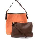 Timeless and modern, our best-selling classic hobo is made in rich vegan leather in a beautiful coral peach color, accented with a coffee brown strap.&nbsp; This roomy bag, accented with a large front pocket and a snap-in removable brown crossbody, has plenty of room to carry your needs in style.


MAIN BAG

12" h x 14" w x 6" d

Adjustable strap 6"-11"

Magnetic snap top closure

Exterior open pocket

Two snaps to attach insert to act as a lining

Brass plated hardware

100% Vegan leather (polyurethane)

R