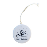 "Merry Christmas" Porcelain Heart Ornament has a bird on a branch with snow falling around it. On the back is two sprigs of evergreen with berries on a snowy background.  2" Dia