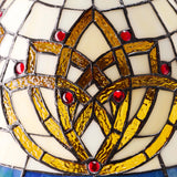 Add Celtic charm to your home with this beautiful 21.5-Inch Celtic Blooming Flower Stained Glass Table Lamp! This exquisite accent fixture masterfully pairs a slender candlestick frame with heritage glasswork to bring a warm presence to your home. The stunning dome shade showcases an intricate blooming flower design that traditionally symbolizes interconnectedness, purity, and renewal. Meticulously crafted using traditional stained glass techniques, it weaves together a vibrant, inviting palette of rich cre