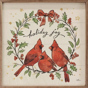 Three red cardinals sit on a holly and berry wreath with a red bow above.  Above the birds, it says "holiday joy" in a cursive font.  It is made from high-quality American hardwood planks with a hand-painted face, printed with UV-cured ink, and framed in a natural walnut frame. Each piece is unique with its own personality, marks, wood grain, and look. Easy to clean with a dry cloth.  Made in the USA  4" x 4" x 1"