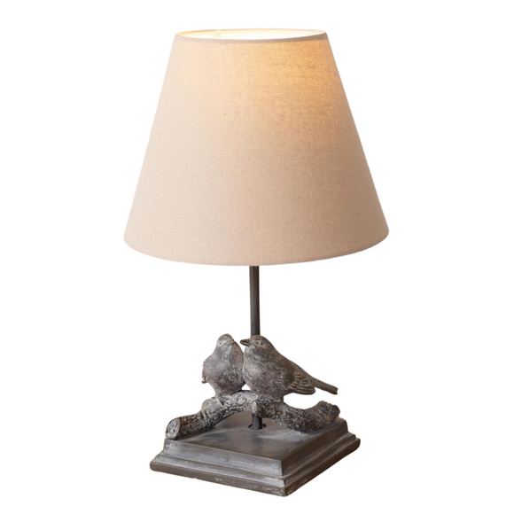 This is such a sweet bird lamp that has two birds sitting on a branch on top of a small square base. The tan linen shade sits above, ready to bring a bright spot to your home!

15