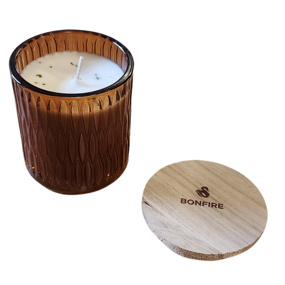You'll love our newest cathedral glass tumbler! This bonfire scent has been poured into a pretty brown patterned glass and comes with a wooden lid.

Charred wood, incense and smoky tones mingle together with the earthiness of oak, fir, and cedar for a true celebration of the senses. Deeply captivating for those who gravitate towards the masculine and mysterious, this cozy fragrance is a true pleasure and invokes the best memories of time spent with friends and family!

Filled with 6.5 oz. of American Soybea