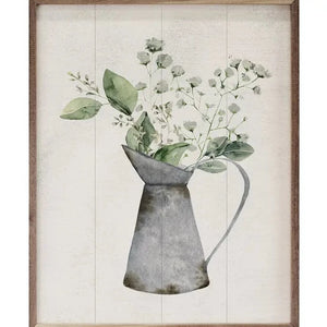 This picture will fit in with so many different decors! There is a distressed galvanized water pitcher in the center of a white background with white flowers and green leaves popping out of the top of it.  Beautiful on its own or in a grouping, you'll find it to be one of your favorite pictures!  This unique piece is a simple way to bring beauty and charm to any wall or shelf within the home.
