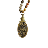 A beautiful long necklace with sections of glass beading with knots in between each bead with a gorgeous oval crazy agate pendant that has a flower detail at the&nbsp;top of the stone. The back of pendant is bronze with scrolled details&nbsp;

Please expect some variation in color/texture due to natural material.

Length: 17" L ( 34" total) with a 2" L pendant