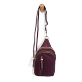 Blending uptown chic with downtown cool, the Skyler sling bag is made in beautiful plum velvet! A convertible strap lends versatility, while a front zip pocket offers practical storage for your necessities. It is the perfect companion for a night out on the town or a fun day trip!  8" h x 5.5" w  x 2.25" d